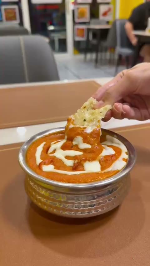 Fresh naan dipped into butter chicken gravy