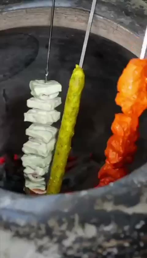 Paneer and vegetable skewers grilling in the clay tandoor